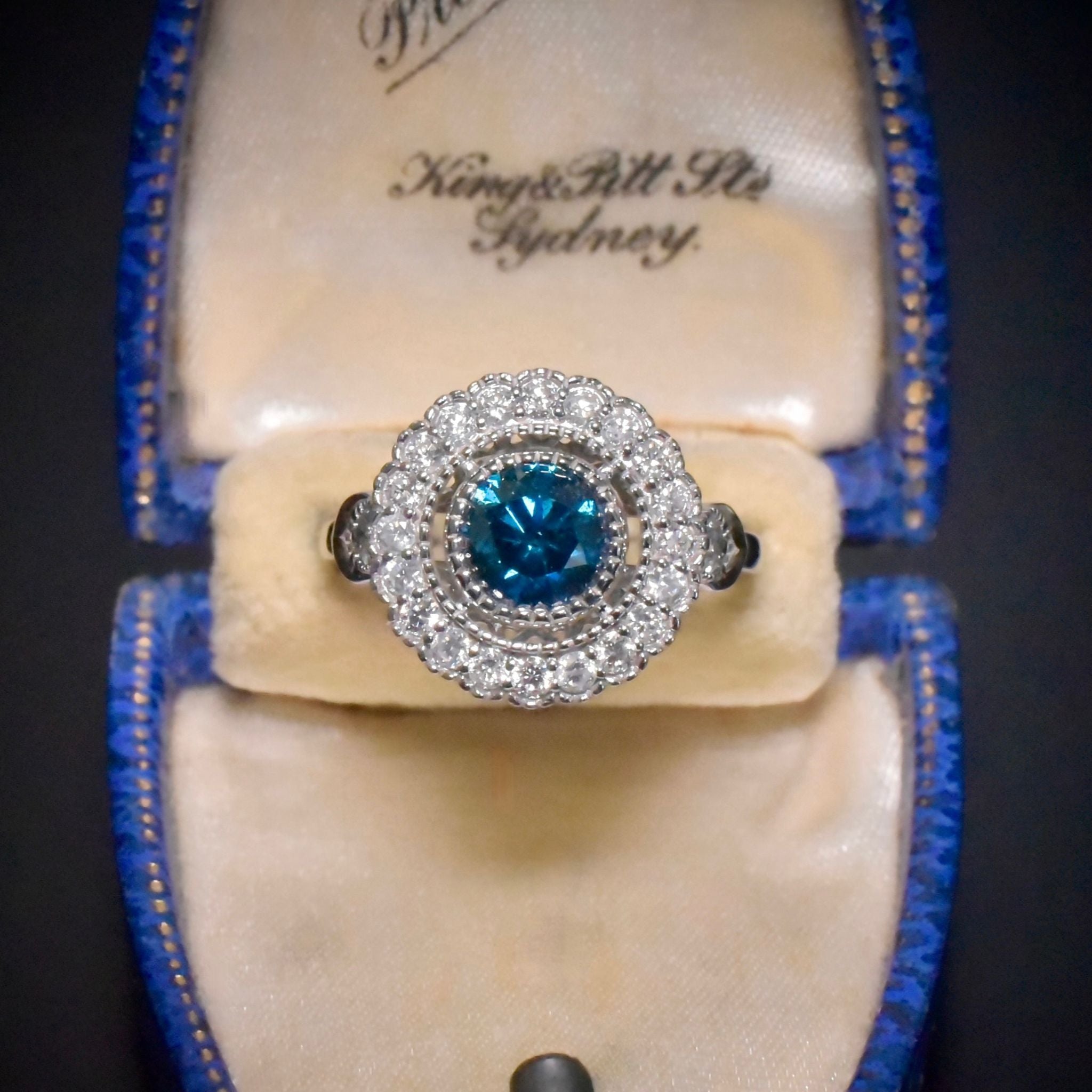 Exquisite 18ct White Gold ‘0.95ct Blue Diamond’ And White Diamond (0.48ct) Halo Ring - Included In Purchase Valuation For $18,600 AUD